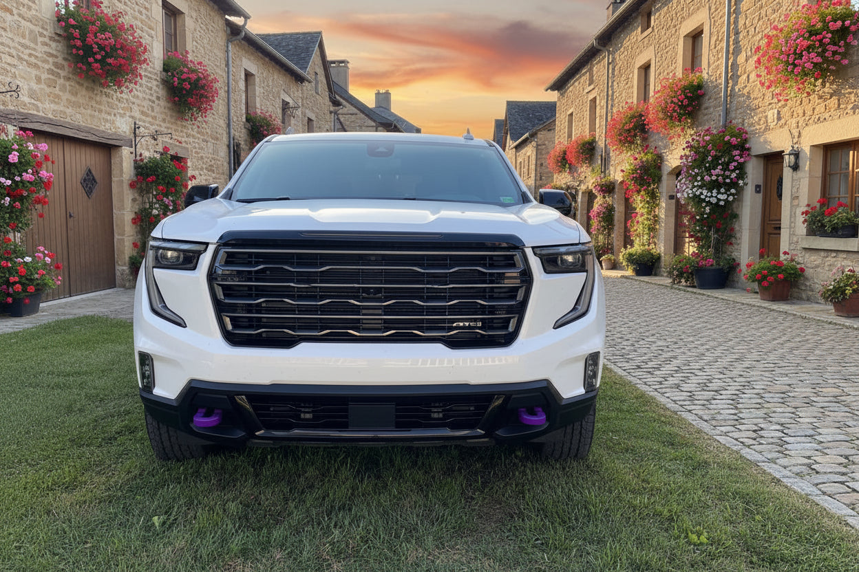 White GMC SUV parked on a grassy area with a scenic village background